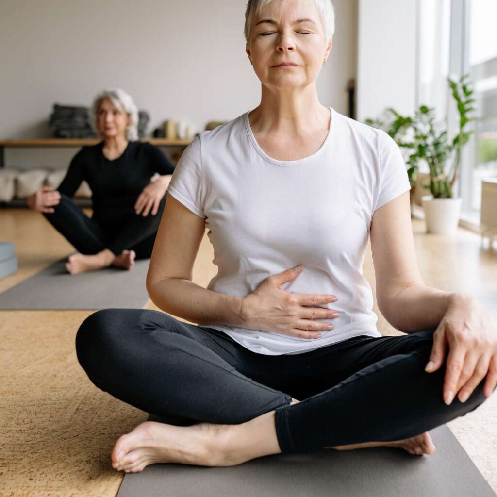 Mujer haciendo Yoga y sosteniendo el estómago